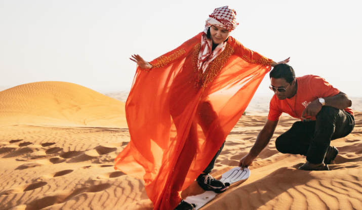 Woman sandboarding in flowing red robe