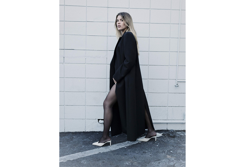 Woman walking in long black coat and white heels