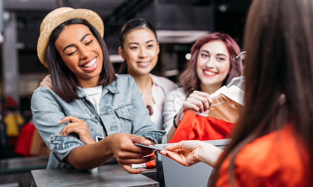 Women smiling while paying at store counter