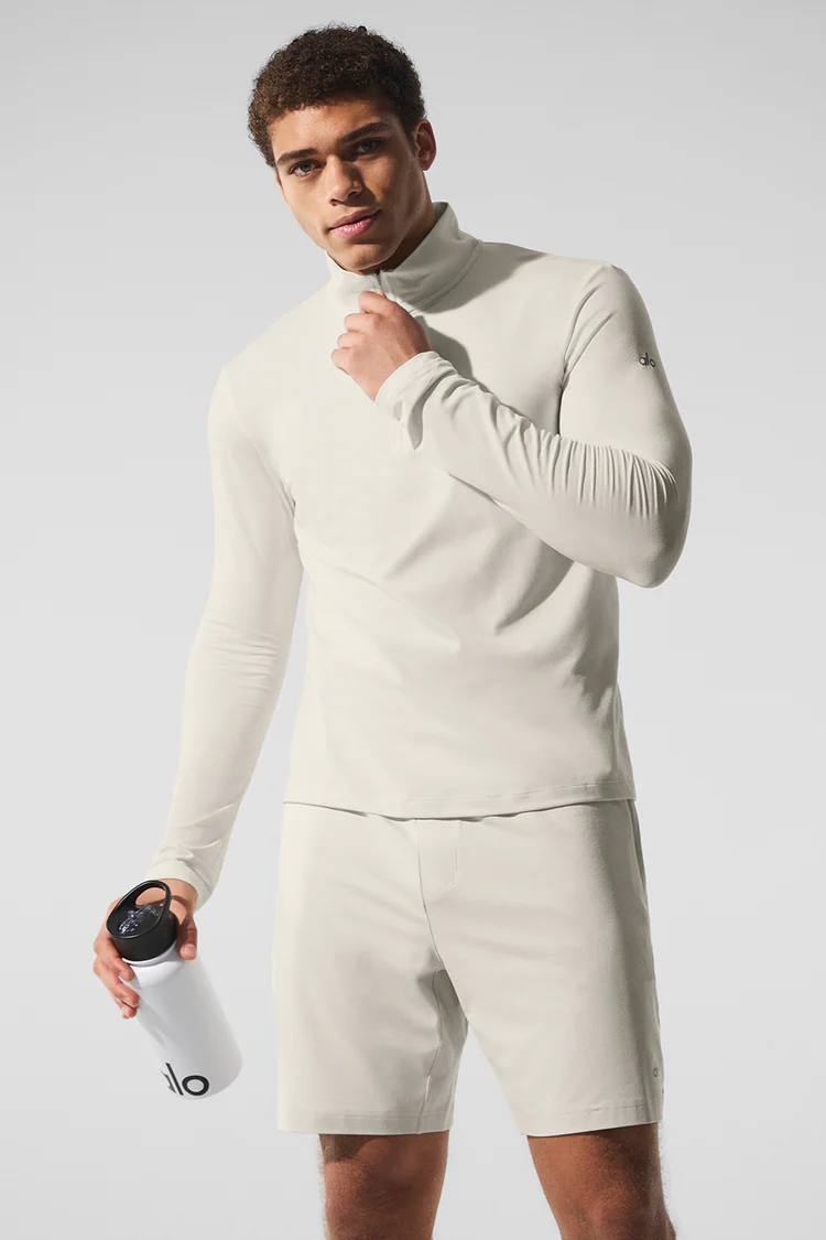 Man wearing light long-sleeve top and shorts holding bottle