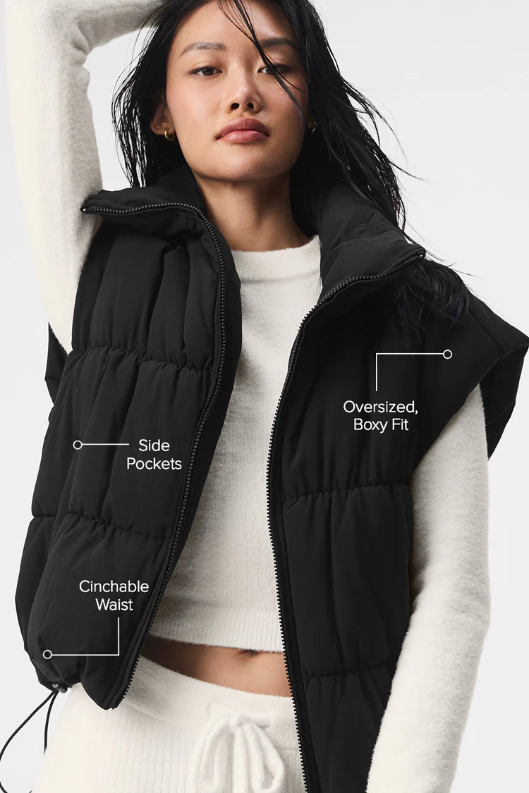Woman wearing black oversized puffer vest with white outfit