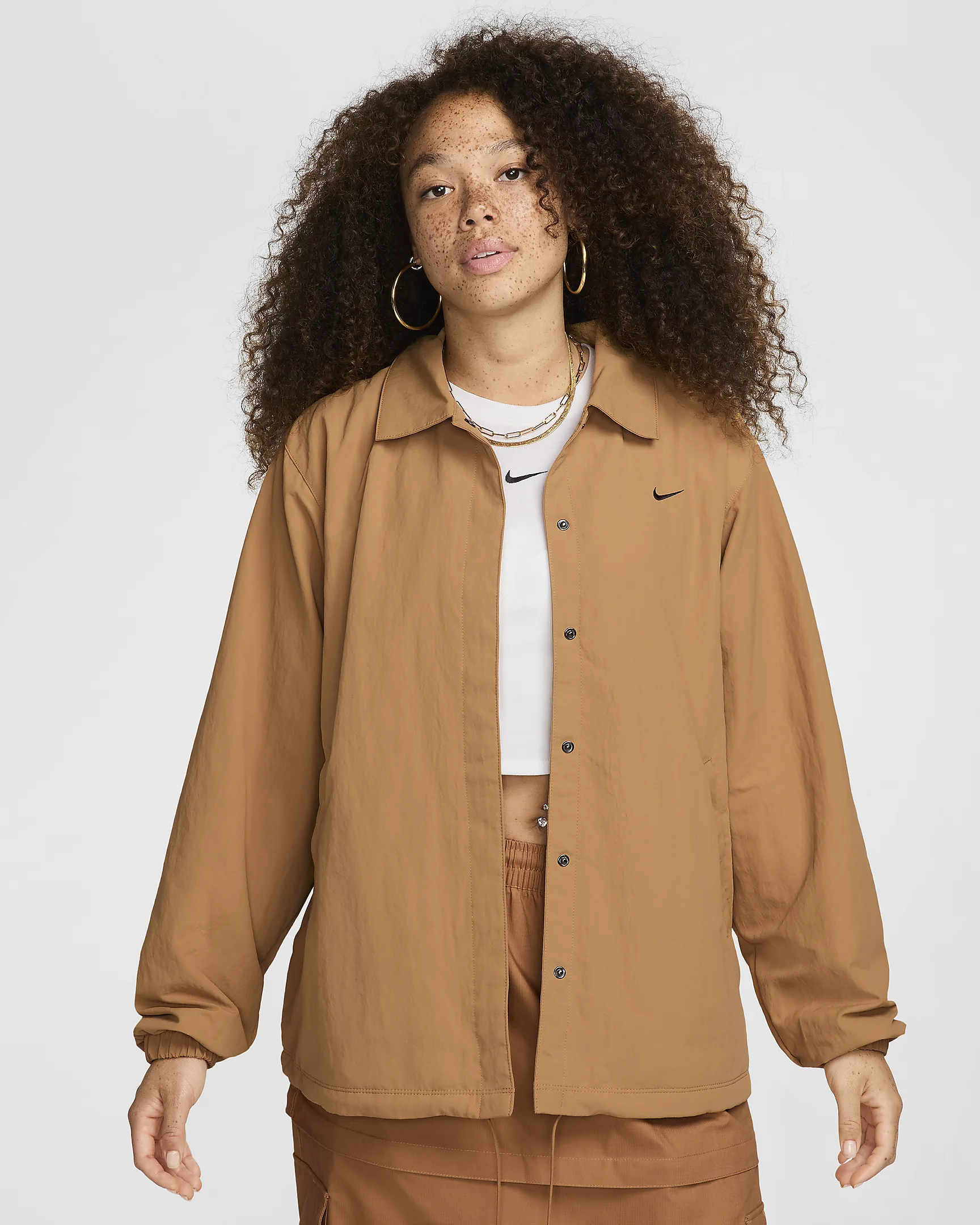 Freckled woman with curly hair wearing tan jacket