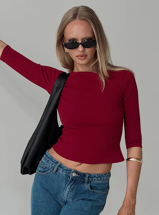 Woman wearing red top, sunglasses, and jeans