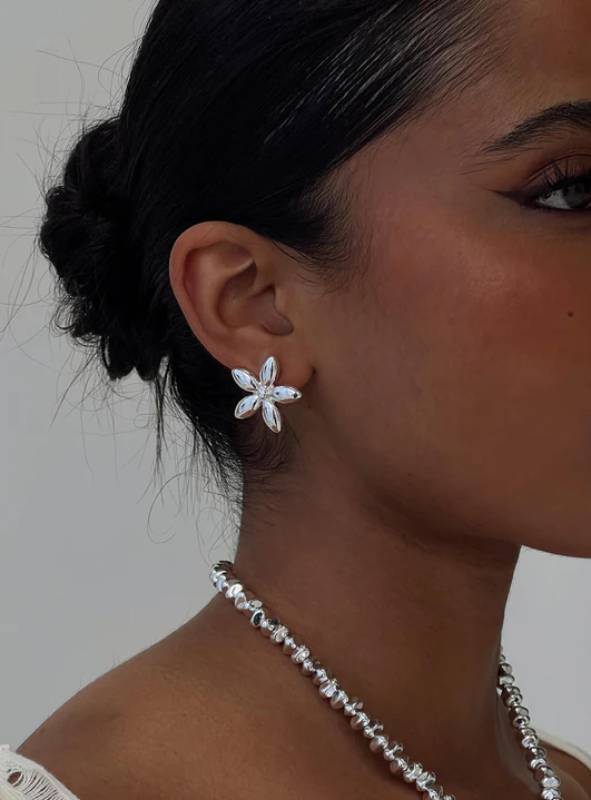 Woman wearing flower-shaped silver earrings and necklace
