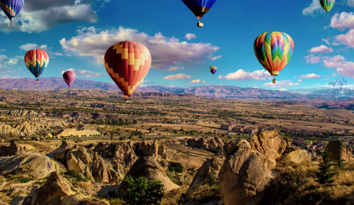 Colorful hot air balloons over rocky landscape and mountains