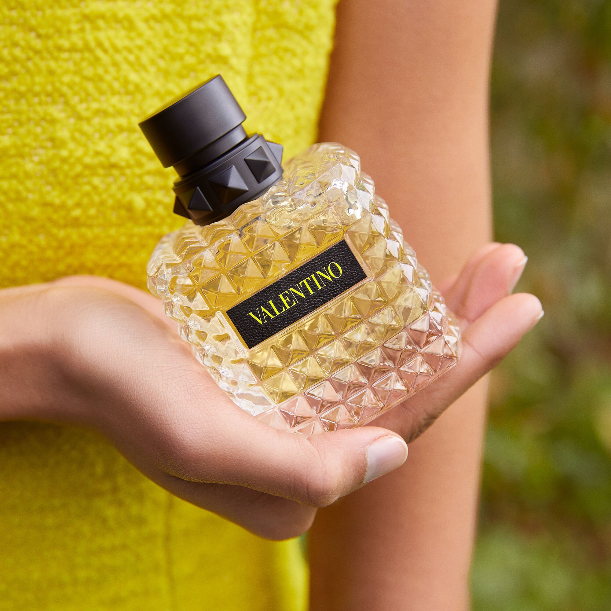 Hand holding Valentino perfume bottle with geometric design