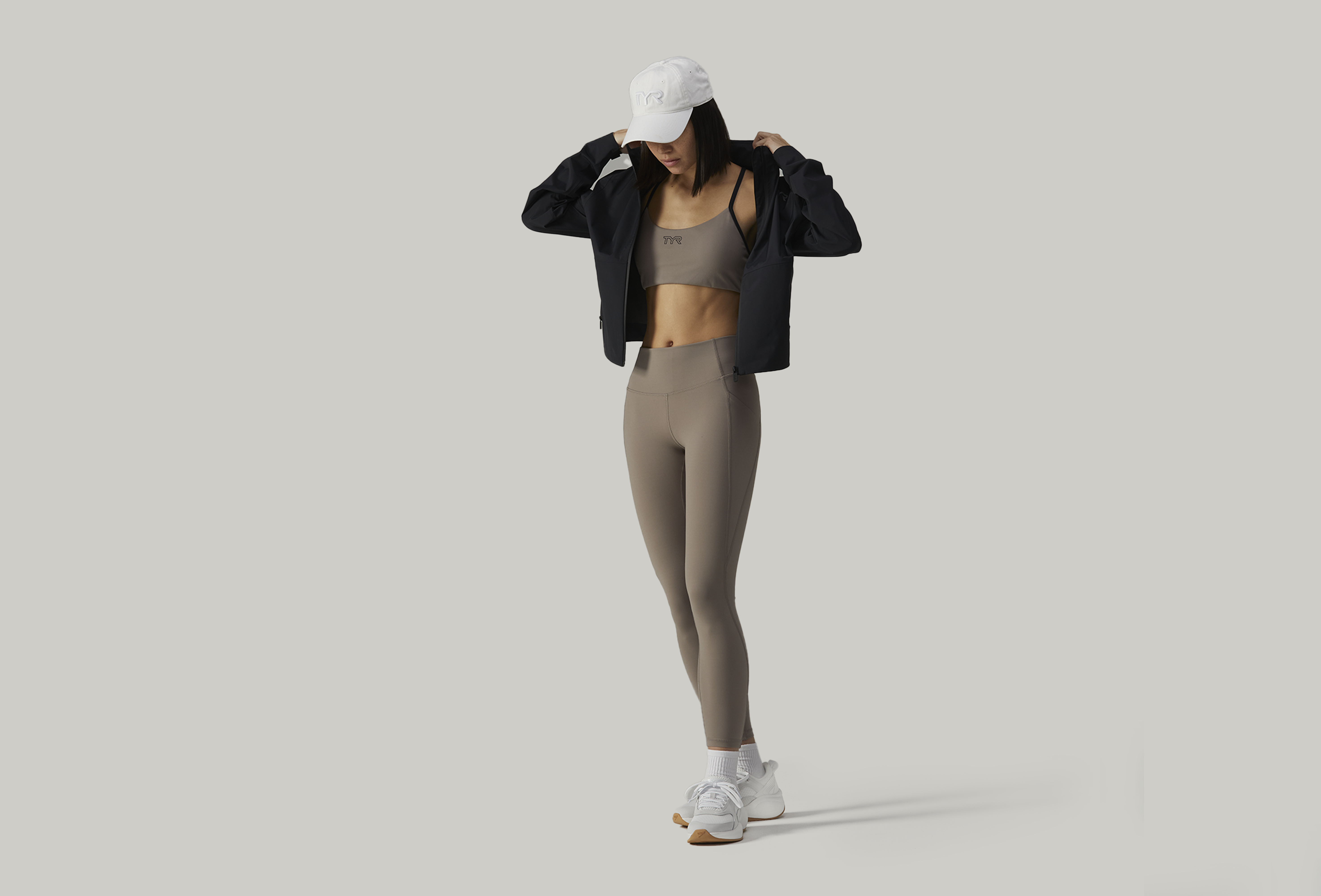 Woman in beige activewear and black jacket