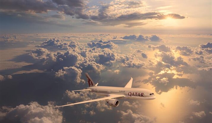 Qatar Airways plane flying above clouds at sunset