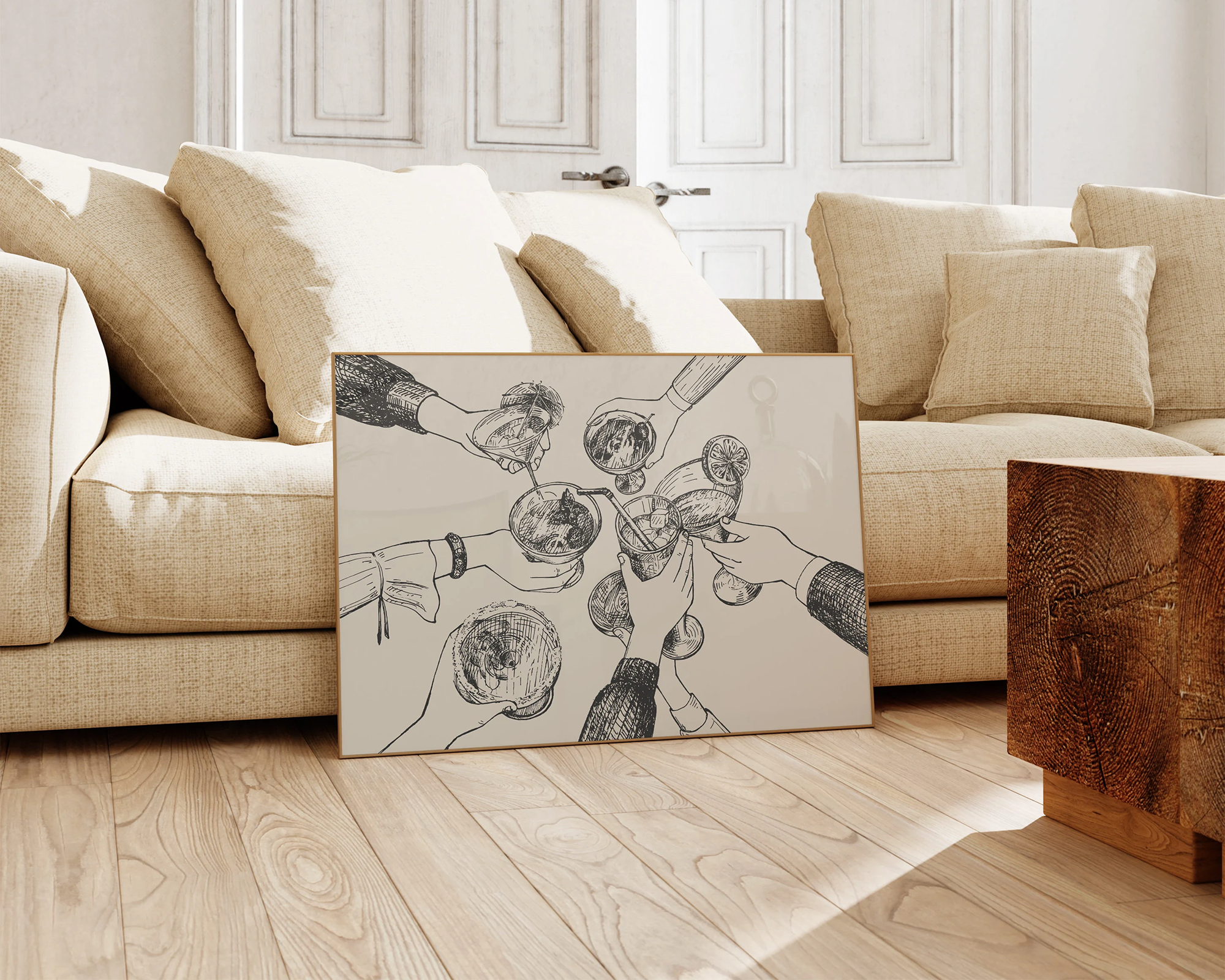 Framed line drawing of hands holding drinks seen from above, leaning against a beige textured sofa in a sunlit, wood-floored living room with a rustic wooden side table.