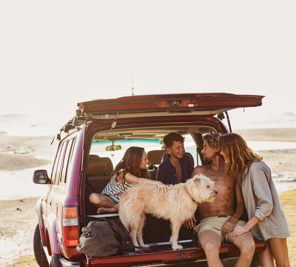 Family with dog enjoying beach sitting in car trunk