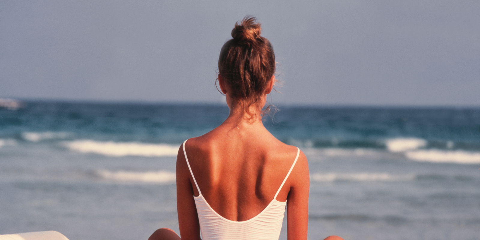 2412_Karma_Woman beach PMI Woman sitting on beach chair facing ocean waves