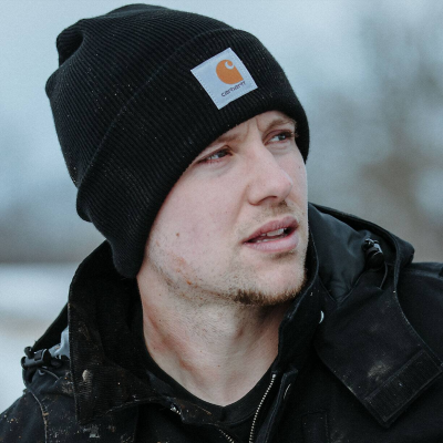Man wearing black Carhartt beanie and jacket outdoors